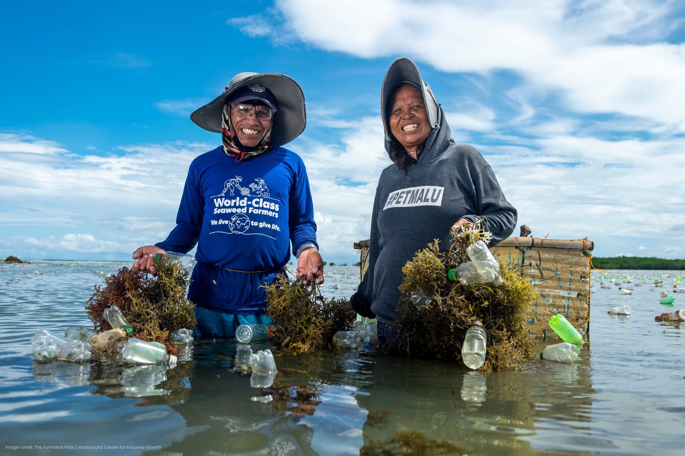 Two seaweed farmers smiling while holding up farmed seaweed.