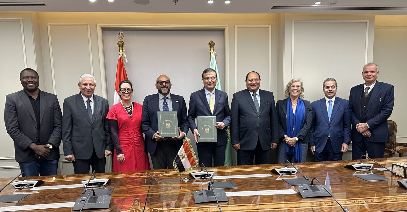 A group of people in a formal wear holding up a partnership agreement.