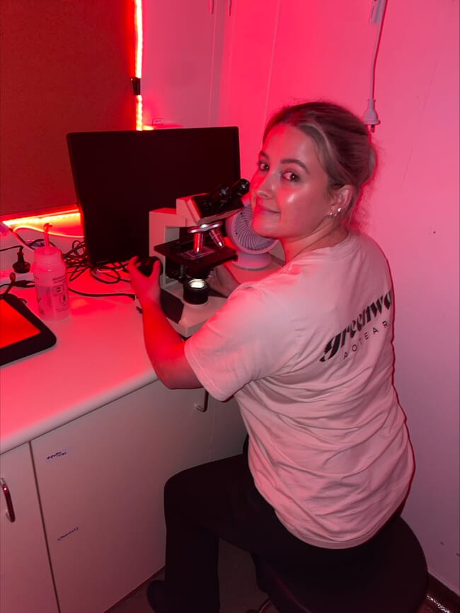 A woman using a microscope in a lab.