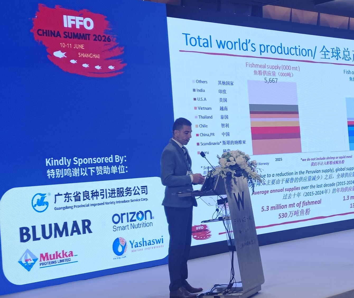 A man in a suit giving a presentation from a stage.