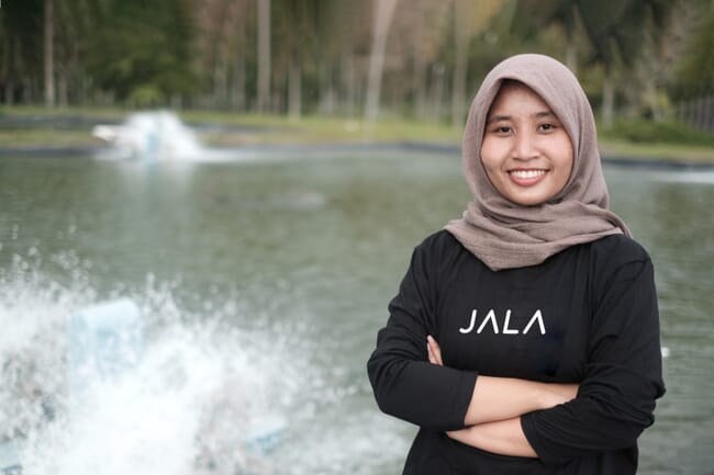 A woman standing in front of a shrimp pond