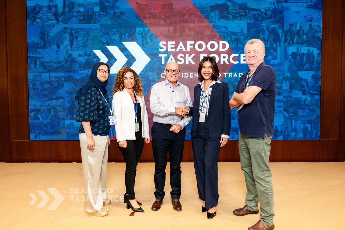 A group of people posing for a photo in a conference lobby.