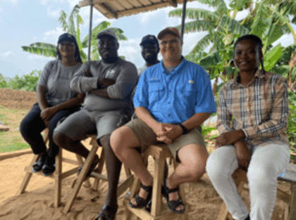 five people sitting under a shade
